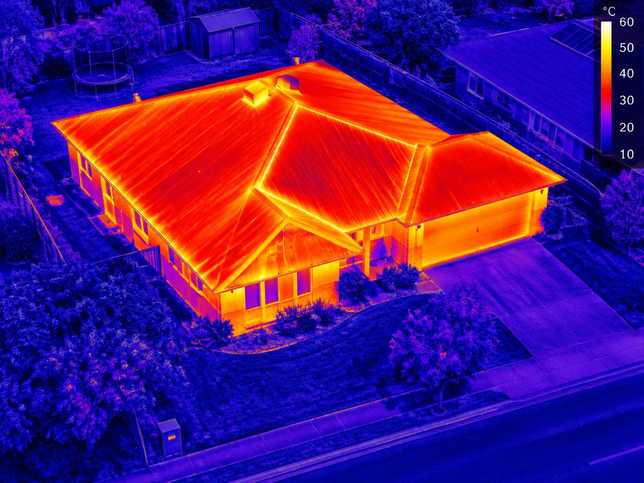 Thermal image of a home before insulation, roof glowing hot
